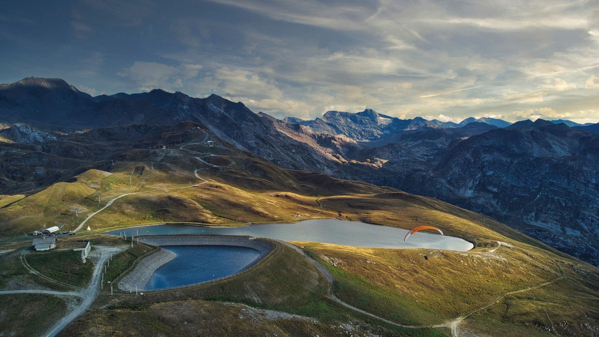 Lac d'altitude et parapente au-dessus des alpages, sommets en fin de journée