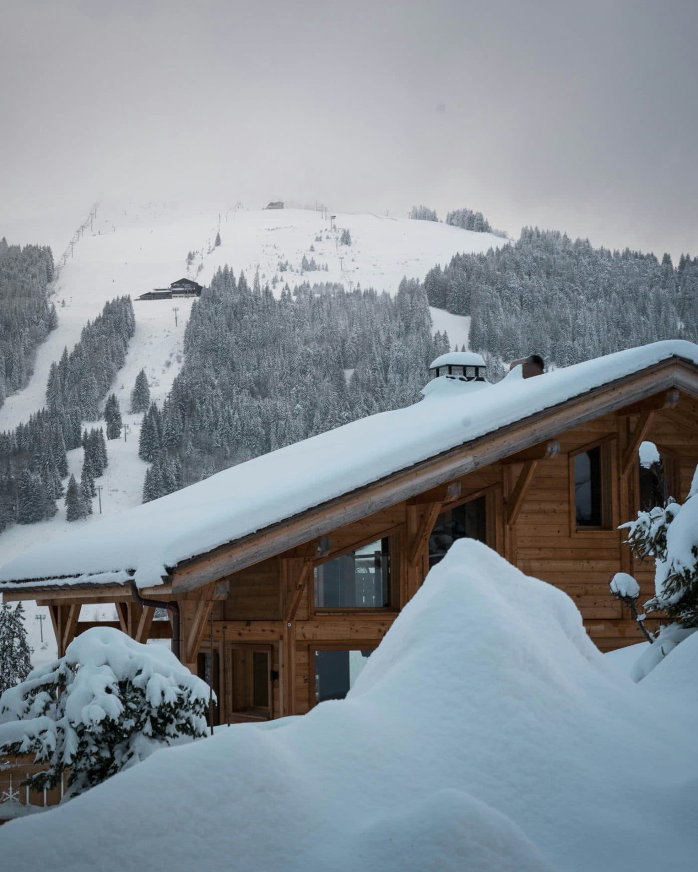 Chalet en bois sous la neige au pied d'une piste de ski